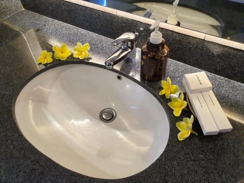 甘地达萨竹笛酒店的浴室的盥洗盆,在台面上摆放着黄色的花卉