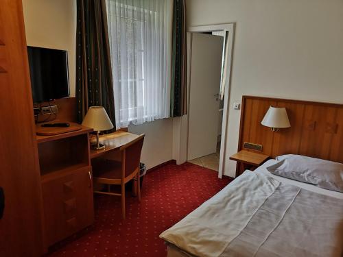 奥尔珀Hotel & Ristorante Il Duomo的酒店客房配有一张床、一张书桌和一台电视。