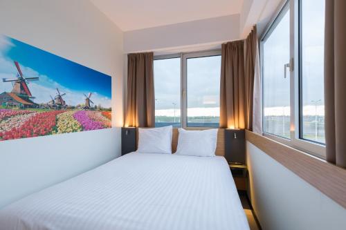 霍夫多普Maxhotel Amsterdam Airport Schiphol的一间卧室配有一张床,窗户配有风车