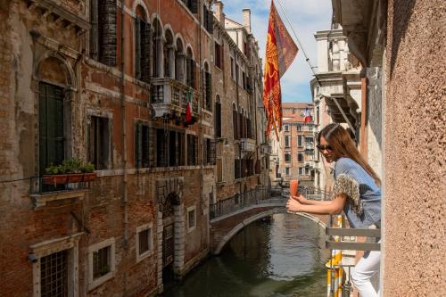 威尼斯鲁奇尼宫酒店的站在阳台上望着运河的女人