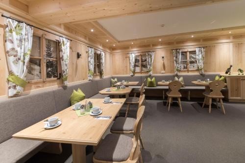 伊施格尔Apart Garni Sesvenna的餐厅设有木桌、椅子和窗户。