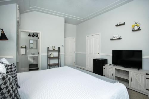 奥克赫斯特犬牙旅馆的白色卧室配有床和平面电视