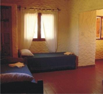 圣玛利亚Cabañas Achalay的一间卧室配有床和带窗帘的窗户