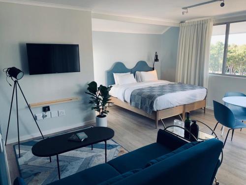 开普敦CURIOCITY Green Point的一间卧室配有一张床和一张蓝色的沙发