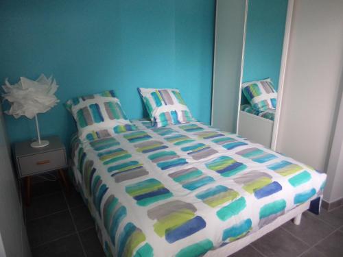 塔尔诺斯T2 Tarnos avec piscine的一间卧室配有一张带五颜六色棉被的床
