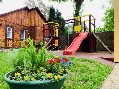 尤尔马拉Jurmala apartment的花园,花园内设有带滑梯和鲜花的游乐场