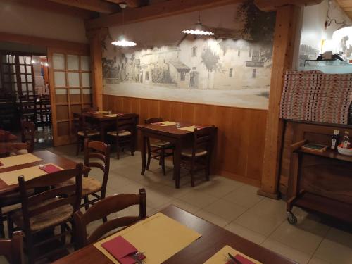 法加尼亚Albergo Baschera的餐厅设有木桌和椅子,墙上挂有壁画