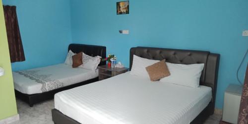 珍南海滩Mazza Nur Motel的一间卧室设有两张床和蓝色的墙壁