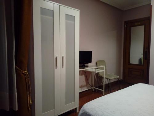 奥维多阿尔瓦雷斯旅舍的一间卧室配有一张床和一张带电脑的书桌