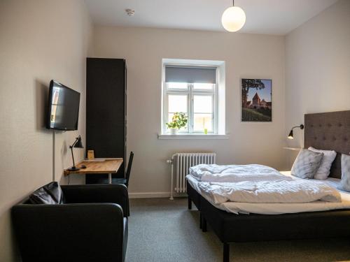 斯泰厄Hotel Residens Møen的一间卧室配有一张床、一把椅子和电视
