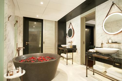 新加坡The Barracks Hotel Sentosa by Far East Hospitality的浴室设有大浴缸,内配红色鲜花