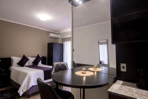 马塞卢Scenery Maqalika Guesthouse的酒店客房带一张床、一张桌子和椅子