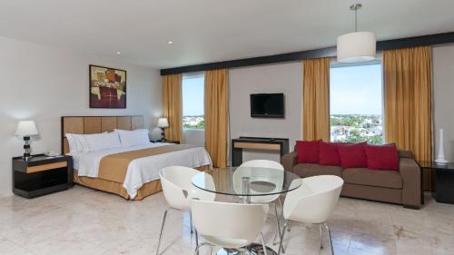 卡门城卡门城智选假日酒店的一间卧室配有一张床、一张沙发和一张桌子