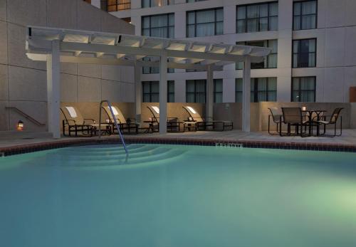 圣安东尼奥圣安东尼奥河滨步道假日酒店的一座带桌椅的游泳池以及一座建筑
