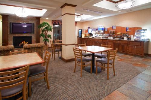 盐湖城Holiday Inn Express Airport East, an IHG Hotel的一间带桌椅和壁炉的餐厅