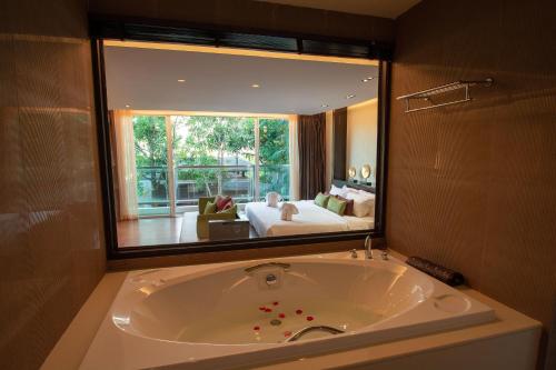 卡伦海滩Peach Blossom Resort & Pool Villa - SHA Plus的一个带大镜子的房间内的大浴缸