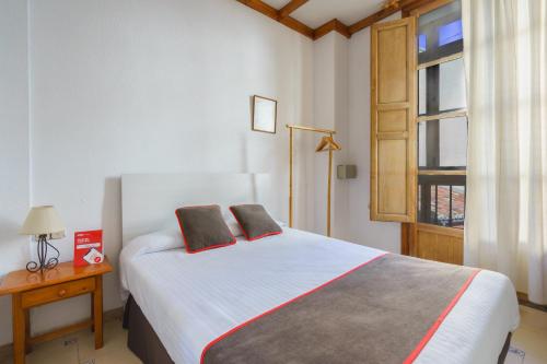格拉纳达Hostal Austria的一间卧室配有一张带两个枕头的床