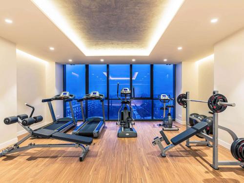阿拉木图阿拉木图市中心美居酒店 的健身房设有有氧器材和大窗户
