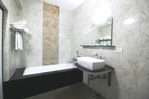 钦奈Saibala Grand Airport Hotel的浴室配有盥洗盆和浴缸。