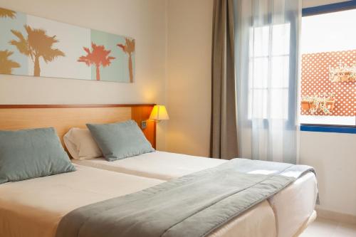 卡门港Grupotel Cinco Plazas的酒店客房设有两张床和窗户。