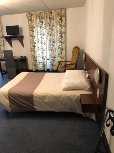 Saint-PaulienHôtel des voyageurs的一间卧室配有床、椅子和窗帘