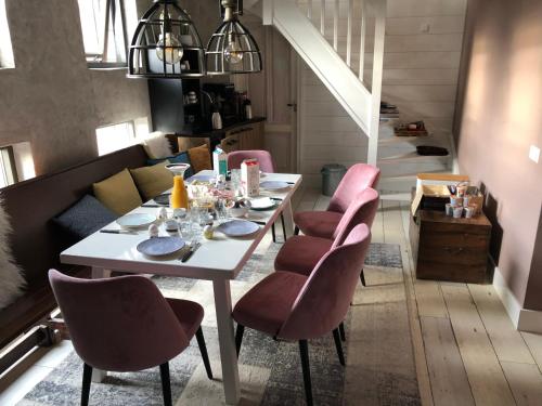 RijnsburgB&B de Petrakerk的一间设有白色桌子和粉红色椅子的用餐室