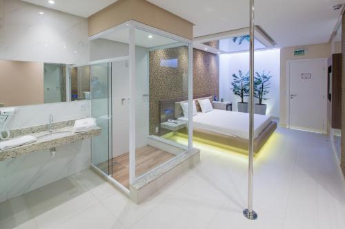 阿拉戈伊尼亚斯MOTEL CLASS的一间带玻璃淋浴的浴室和一张床