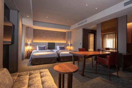 京都Tokyu Stay Kyoto Sakaiza Shijo Kawaramachi的酒店客房设有两张床和一张桌子。