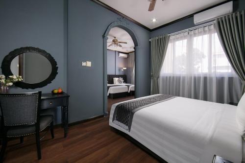 万象Vientiane Boutique Hotel的一间卧室配有一张床、一张书桌和一面镜子