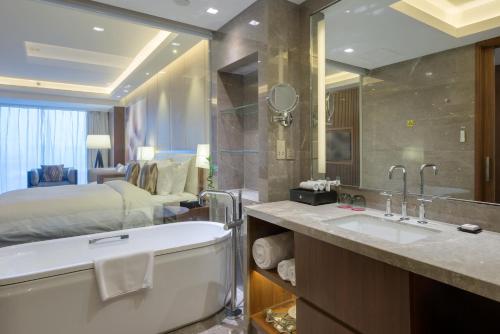 济南济南鲁能贵和洲际酒店的一间带床、浴缸和水槽的浴室