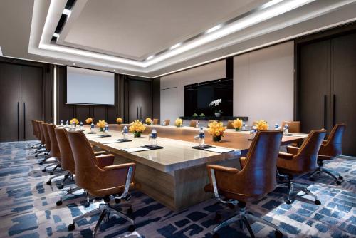 上海上海建工浦江皇冠假日酒店的大型会议室,配有长桌子和椅子