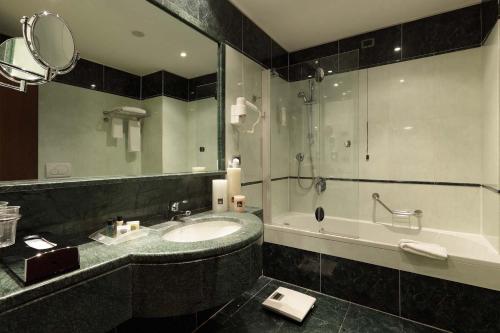 都灵都灵科索弗朗西亚假日酒店的一间带水槽、浴缸和镜子的浴室