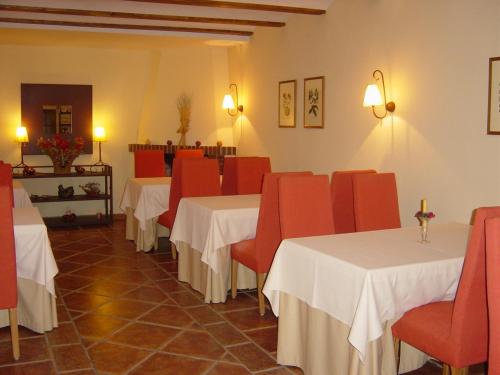 MandayonaHostal Rural Cumbres De Castilla的一间带两张桌子和红色椅子的餐厅