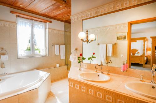 Brunegg三颗星浪漫酒店的浴室配有2个盥洗盆、浴缸和大镜子