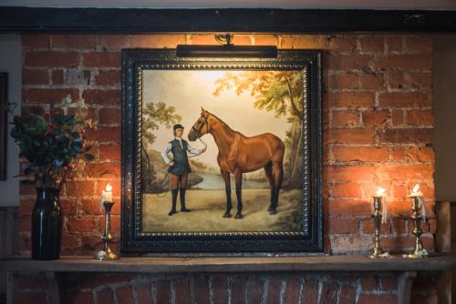 奇切斯特The Horse and Groom Inn的墙上一幅画,画着一匹人和一匹马