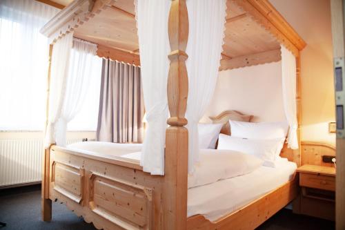 杜伊斯堡隆纳克酒店的一间卧室配有一张带白色床单的四柱床