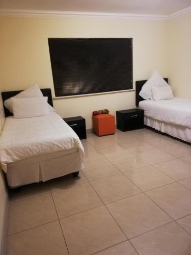 鲁德普特Rocky Ridge Guest House 2 SELF CATERING - No Alcohol allowed的客房设有两张床和一台平面电视。