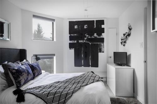 惠斯勒The Modern Whistler Apartment - Ski-in ski-out的一间卧室配有一张床和一台电视
