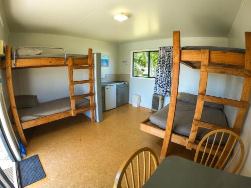 玛拉豪Marahau Beach Camp的客房设有两张双层床和一张桌子及椅子。