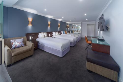 悉尼海德公园酒店的客房设有一排床铺和一张书桌