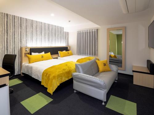 仓敷Green Rich Hotel Kurashiki Ekimae (Artificial hot spring Futamata Yunohana)的一间卧室配有一张带黄色枕头的大床和一张沙发