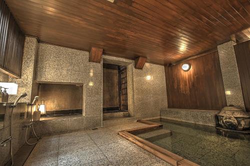 伊东伊东温泉K's - 历史旅舍的带浴缸的浴室和木制天花板