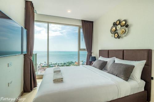 乔木提恩海滩The Riviera Jomtien Sea View的一间卧室设有一张大床和大窗户