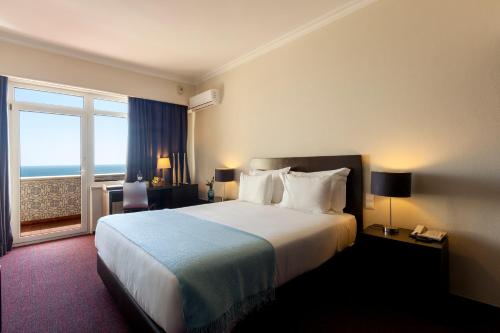 卡尔卡维洛斯Carcavelos Beach Hotel的酒店客房设有一张床和一个大窗户