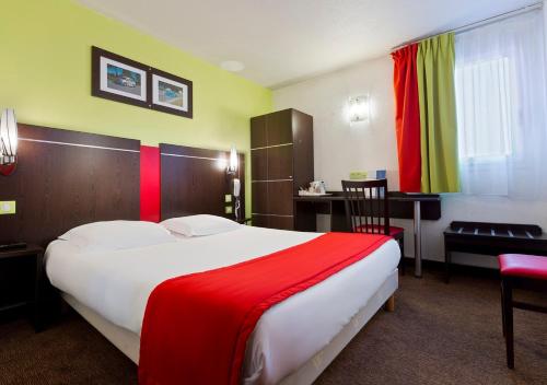兰斯Enzo Hotels Reims Tinqueux by Kyriad Direct的酒店客房设有一张大床和一张书桌。