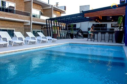 恩卡纳西翁日落酒店的一座带椅子的游泳池,一座女游泳池就位于大楼旁边