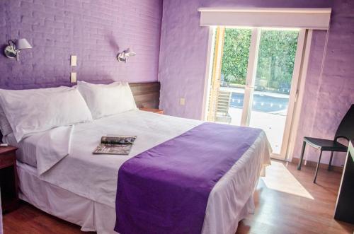 埃斯特角城Punta del Este San Marcos Eco Hotel的紫色卧室设有一张大床和一个窗户