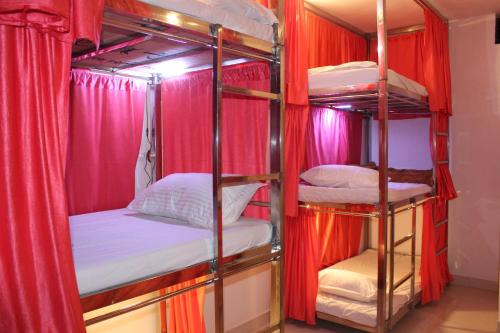 奥拉奇哈Sunset Backpackers Hostel的一间设有四张双层床和红色窗帘的房间