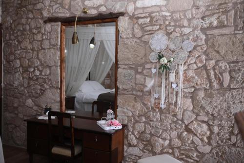 KormakitiHanna Koumi Boutique Hotel的一间卧室配有带镜子的石墙和书桌