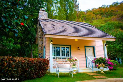 慕斯小屋 @ 山区度假村的院子里带长凳的粉红色小房子